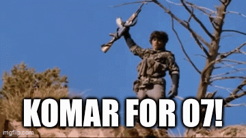 A Man Holding A Gun With The Words Komar For 07 Written Below Him GIF