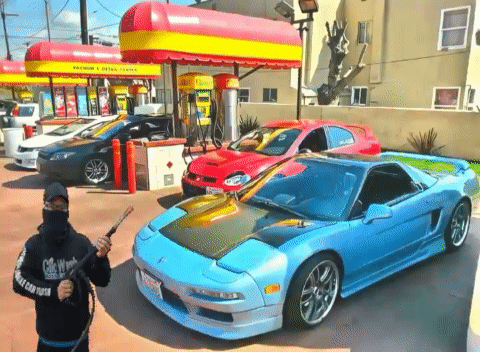A Man Holding A Hose In Front Of A Car With A License Plate That Says California GIF
