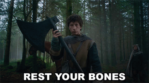 A Man Holding A Large Axe In A Forest With Rest Your Bones Written On The Bottom GIF