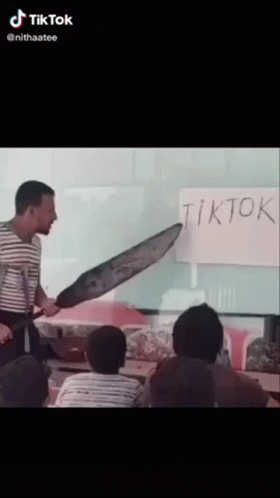 A Man Holding A Large Knife In Front Of A White Board That Says Tiktok GIF