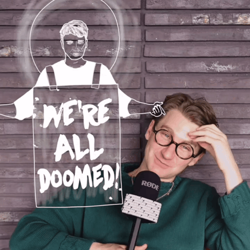 A Man Holding A Microphone In Front Of A Sign Saying We 'Re All Doomed GIF