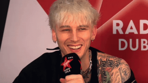 A Man Holding A Microphone That Says Virgin Radio 104.4 On It GIF