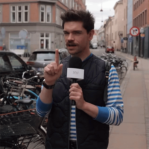 A Man Holding A Microphone With The Letter Mh On It GIF
