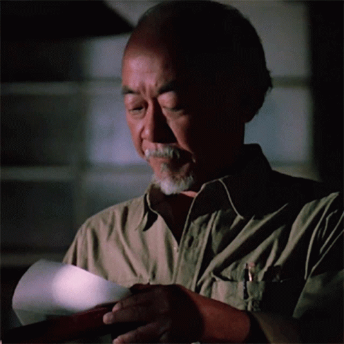 A Man Holding A Piece Of Paper With A Pen In His Pocket GIF