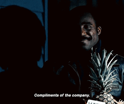 a man holding a pineapple and a card that says compliments of the company on it