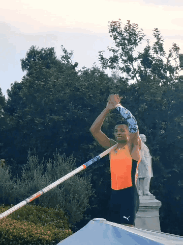 A Man Holding A Pole In Front Of A Statue Of A Man GIF
