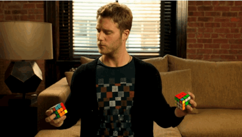 A Man Holding A Rubik 'S Cube In His Hands GIF