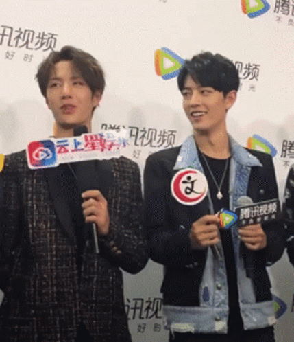 A Man Holding A Sign That Says ' A ' On It Stands Next To Another Man GIF