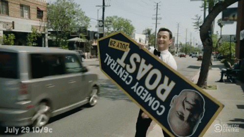 A Man Holding A Sign That Says " Comedy Central " GIF