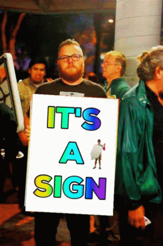 A Man Holding A Sign That Says " It 'S A Sign " GIF