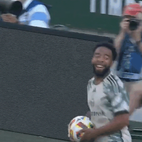 A Man Holding A Soccer Ball With A Shirt That Says Allmook On It GIF