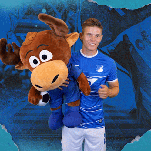 A Man Holding A Stuffed Moose Wearing A Blue Shirt That Says Tsg GIF