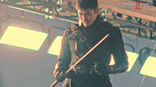 A Man Holding A Sword In Front Of A Sign That Says Snakeeyes GIF