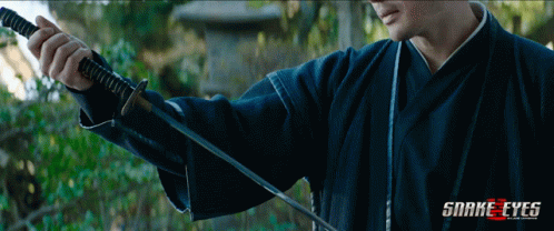 A Man Holding A Sword With Snake Eyes Written On The Bottom Right GIF