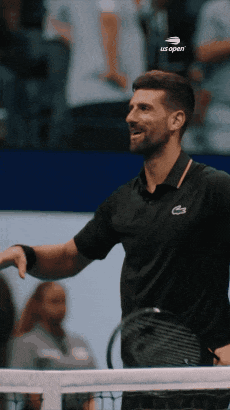 A Man Holding A Tennis Racquet And Wearing A Black Shirt That Says Us Open GIF