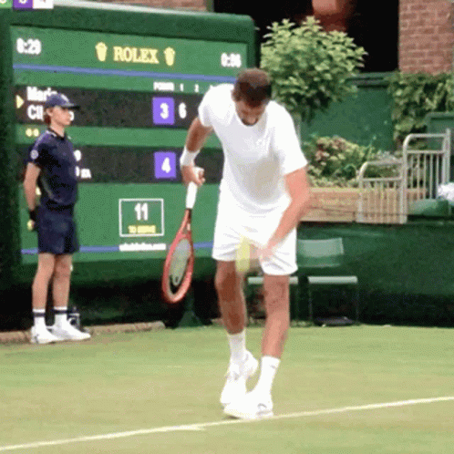 A Man Holding A Tennis Racquet In Front Of A Scoreboard That Says Rolex On It GIF