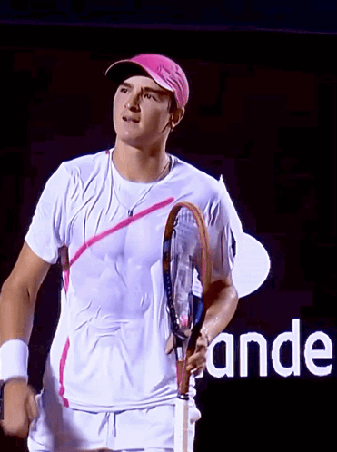 A Man Holding A Tennis Racquet In Front Of A Sign That Says " Ande " GIF