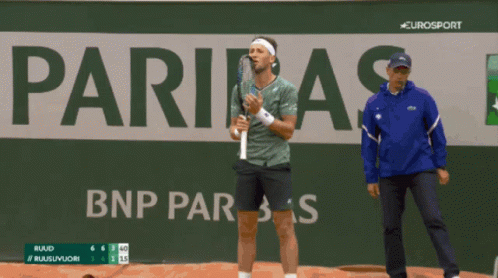 A Man Holding A Tennis Racquet In Front Of A Sign That Says Eurosport GIF
