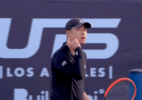 A Man Holding A Tennis Racquet In Front Of A Sign That Says U.s. GIF