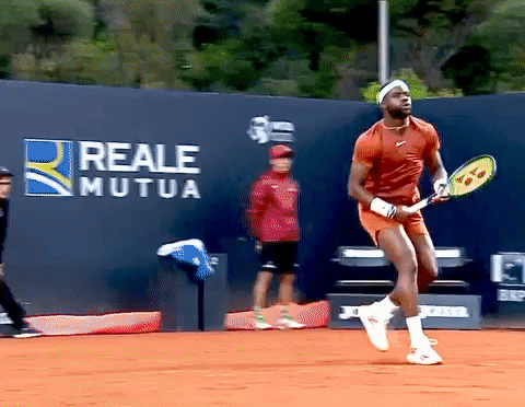 a man holding a tennis racquet in front of a wall that has reale mutua written on it
