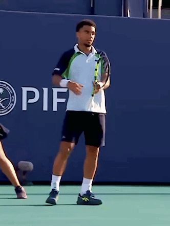A Man Holding A Tennis Racquet In Front Of A Wall That Says If On It GIF