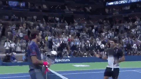 A Man Holding A Tennis Racquet On A Tennis Court In Front Of A Crowd Sponsored By Spectrum GIF