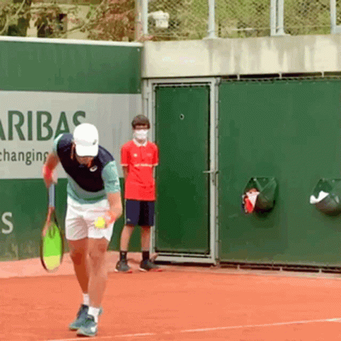 A Man Holding A Tennis Racquet On A Tennis Court In Front Of A Sign That Says Aribas GIF