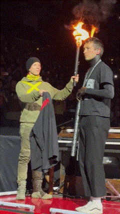 A Man Holding A Torch Stands Next To A Woman Holding A Jacket GIF