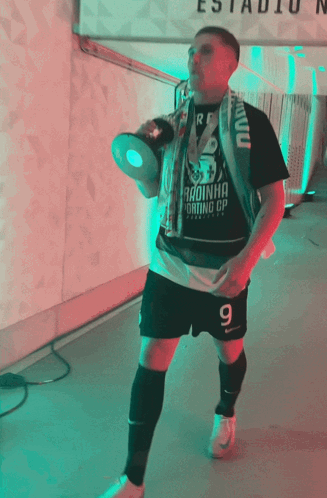 A Man Holding A Trophy And Wearing A Shirt That Says " Radinha " GIF