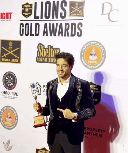 A Man Holding A Trophy At The Lions Gold Awards GIF