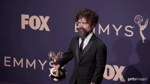 A Man Holding A Trophy In Front Of A Sign That Says Fox GIF
