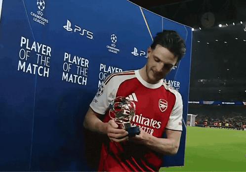 A Man Holding A Trophy In Front Of A Sign That Says " Player Of The Match " GIF