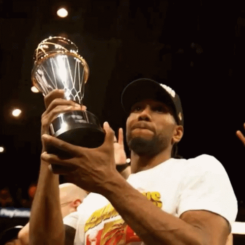 A Man Holding A Trophy That Says ' Nba ' On The Front GIF
