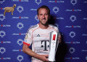 A Man Holding A Trophy With The Letter T On His Shirt GIF