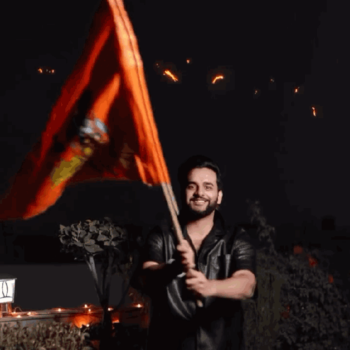 A Man Holding An Orange Flag In Front Of A Sign That Says ' I ' On It GIF