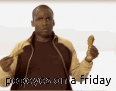 A Man Holding Up A Chicken Wing With The Words Popeyes On A Friday Written Below Him GIF