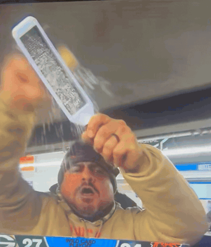 A Man Holding Up A Knife In Front Of A Scoreboard With The Number 27 On It GIF