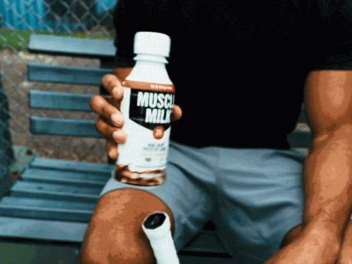 A Man Holds A Bottle Of Muscle Milk In His Hand GIF