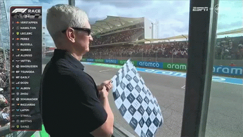 A Man Holds A Checkered Flag In Front Of A Screen That Says Espn On It GIF