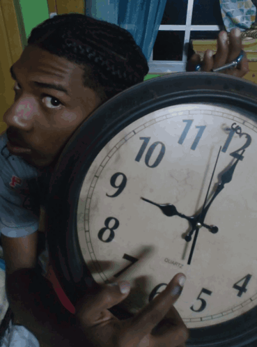 A Man Holds A Clock That Says Quartz On The Face GIF