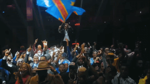 A Man Holds A Flag In Front Of A Crowd Of People GIF