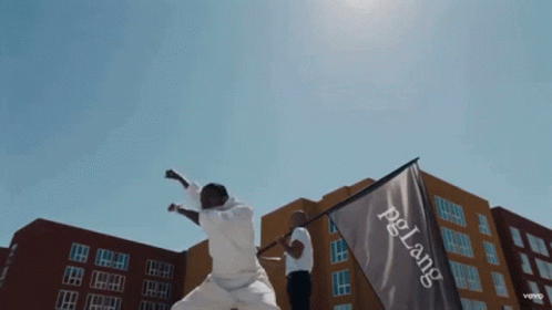 A Man Holds A Flag That Says Pelang On It GIF