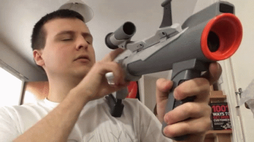 A Man Holds A Toy Gun In Front Of A 100 Ways To Win Customers Book GIF