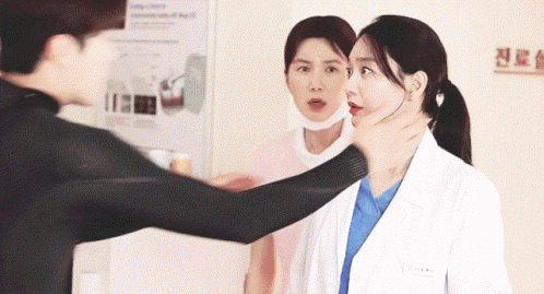 A Man Holds A Woman 'S Neck While A Nurse Looks On GIF