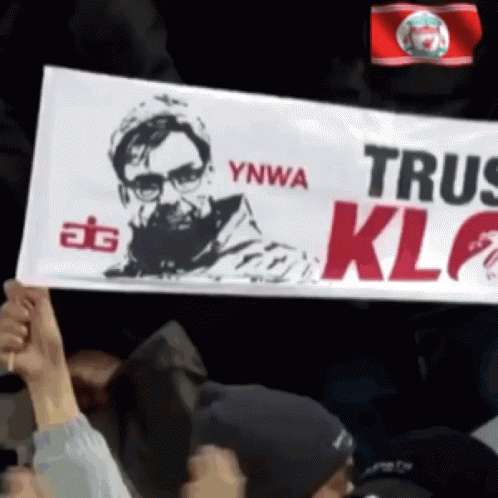 a man holds up a sign that says ynwa trus klf