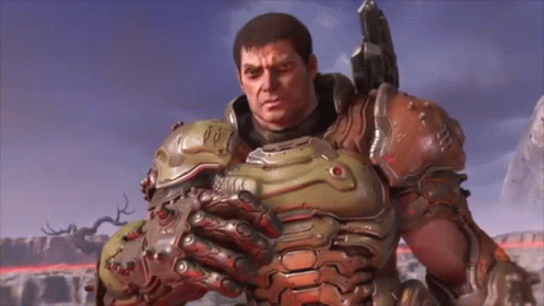 A Man In A Armored Suit Is Holding A Gun And Looking At The Camera . GIF