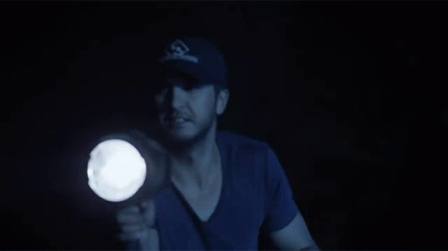 A Man In A Baseball Cap Holds A Flashlight GIF