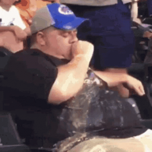 A Man In A Baseball Cap Is Drinking Water From A Bottle . GIF