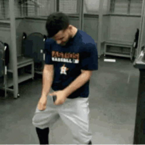A Man In A Baseball Uniform Is Dancing In A Locker Room GIF