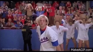 A Man In A Baseball Uniform Is Standing In Front Of A Crowd Of Cheerleaders In A Stadium . GIF